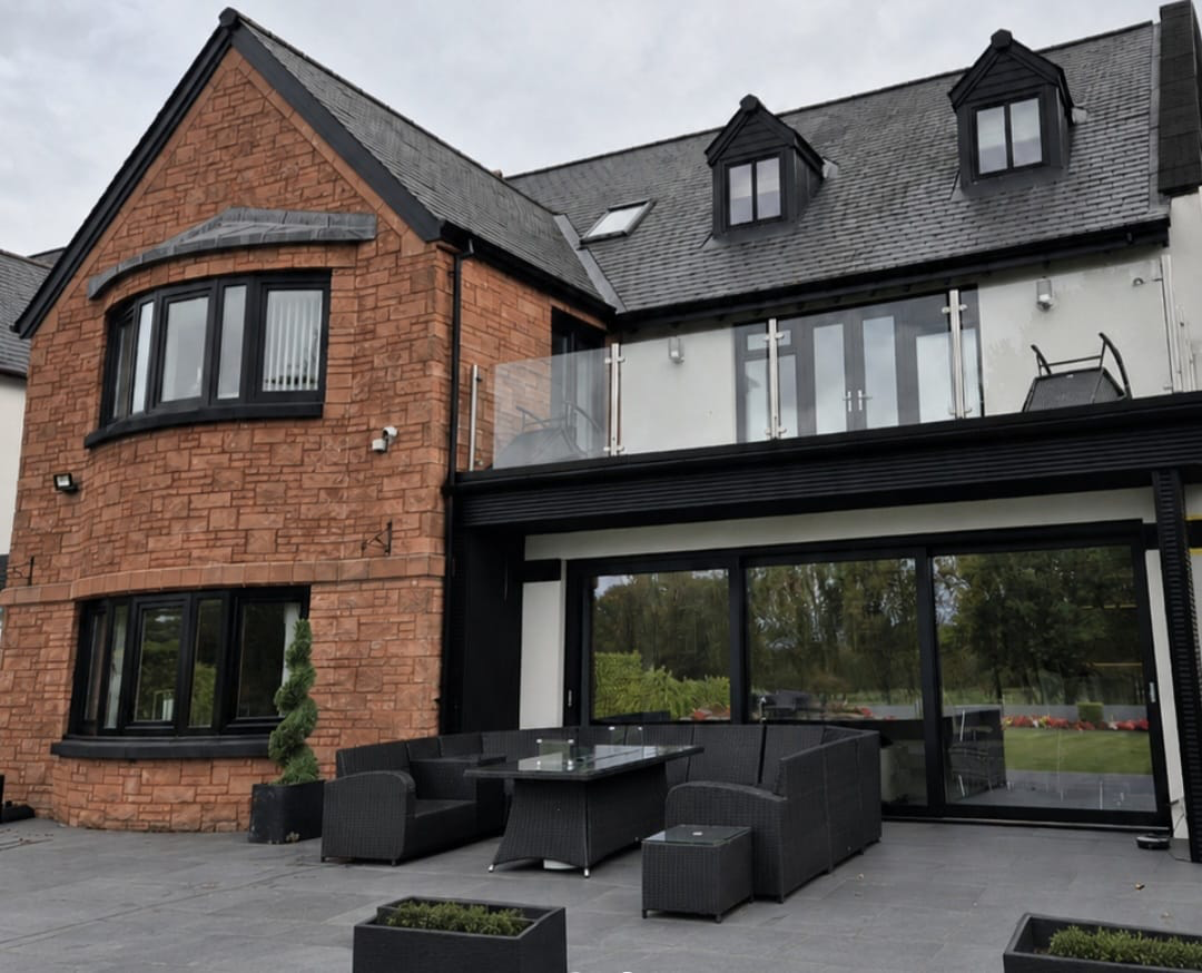Luxury stone-clad Glasgow home with sprayed black windows, bi-folds and roofline